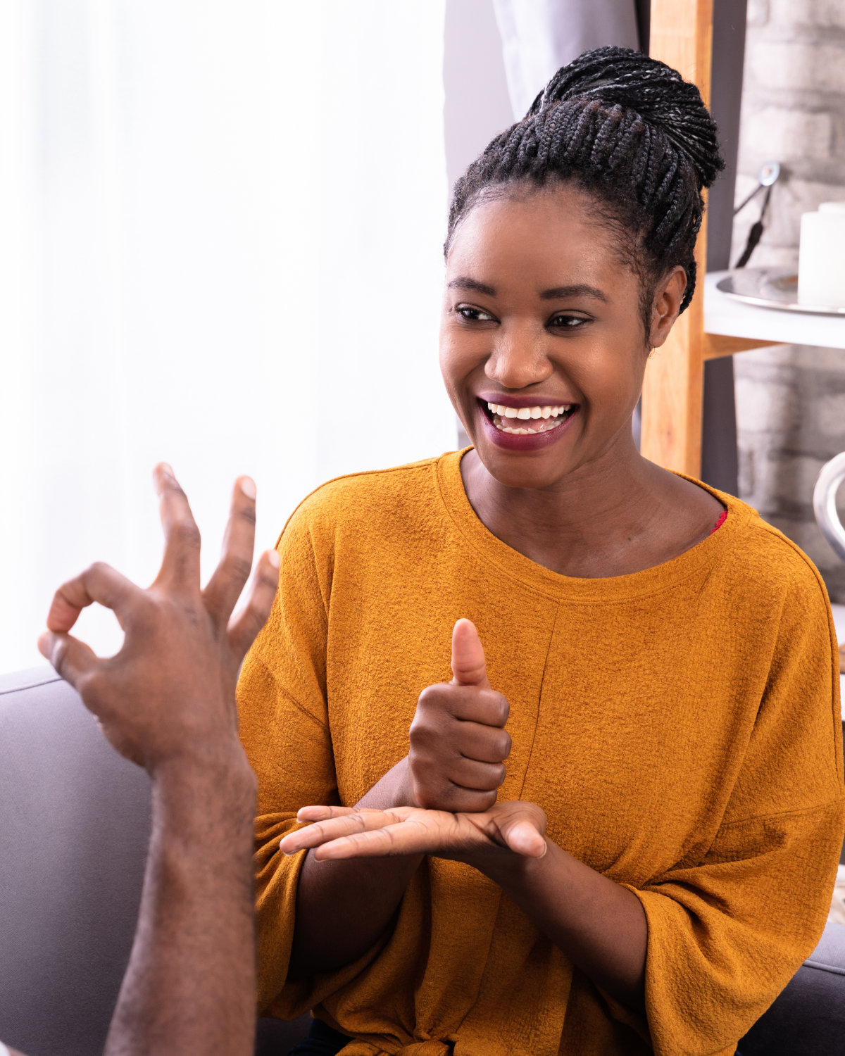 Two people smiling as they have a conversation in British Sign Language.